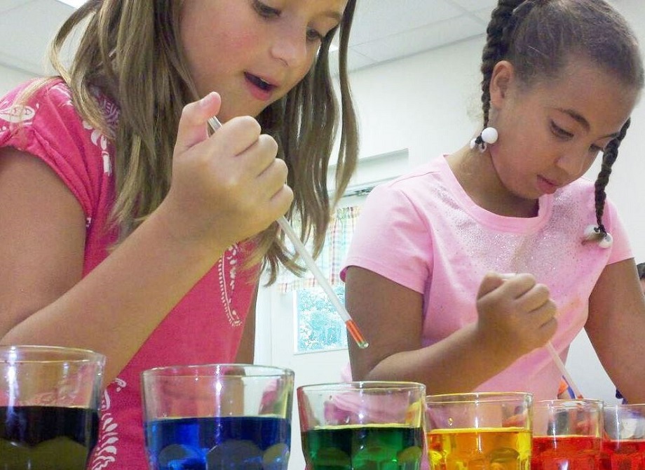 Two girls working on a science experiment with droppers and beakers