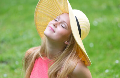 Woman looking to the sky with her eyes closed in an open field