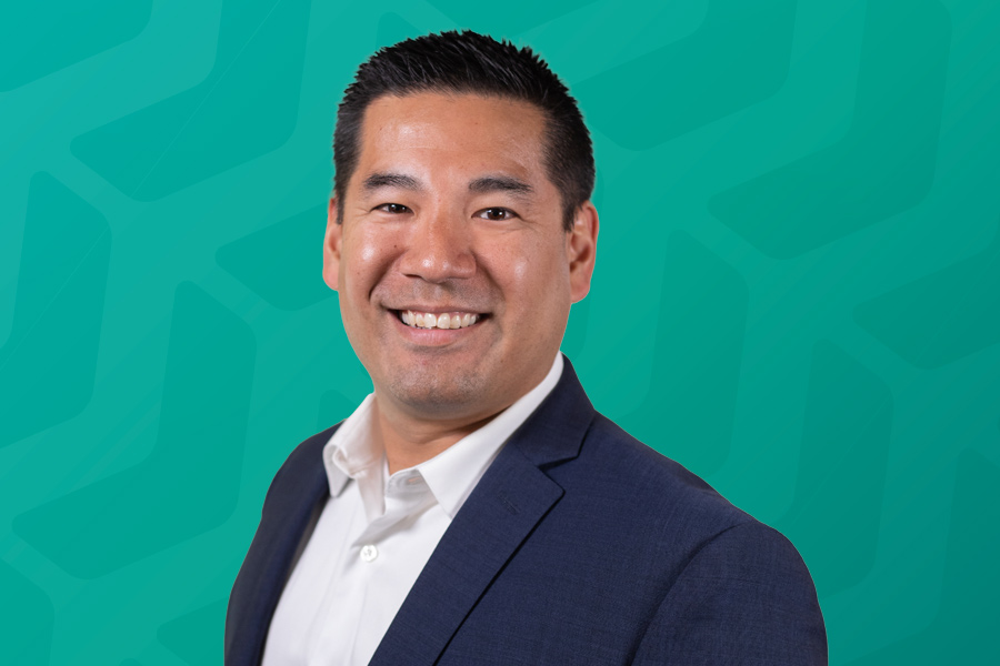 Headshot of Justin Higa in front of green chevron background