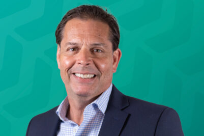 Headshot of Tom Verzi in front of green chevron background
