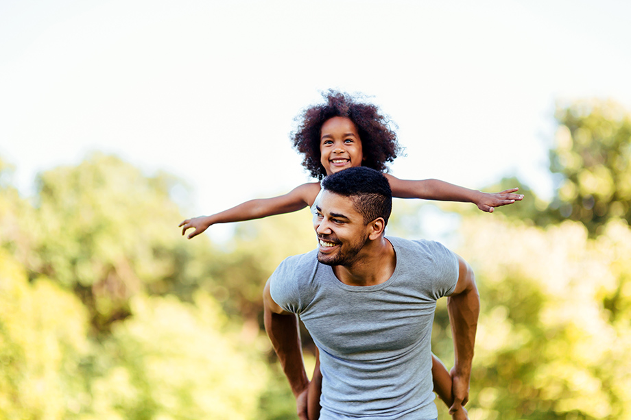 Portrait of young father carrying his daughter on his back
