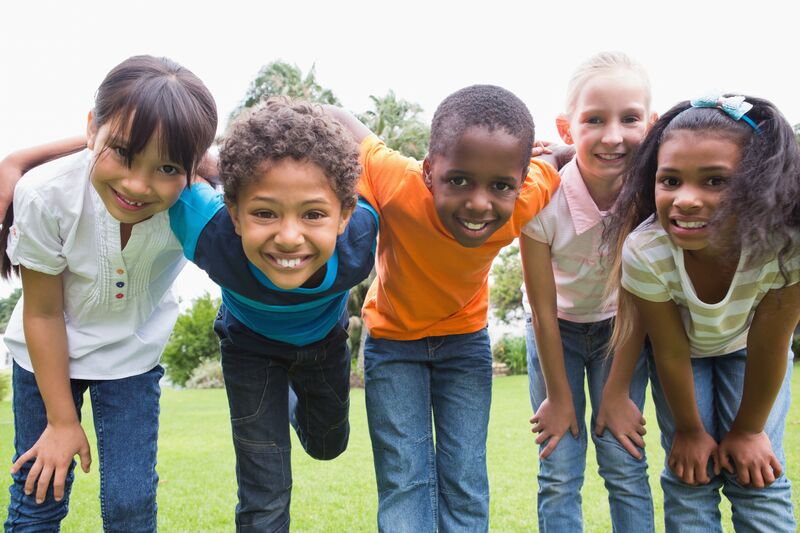 Group of multicultural kids hugging together in an open field