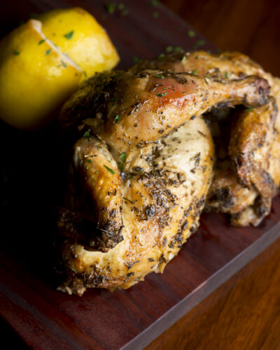 Cornish Game Hen in pan with lemon wedge
