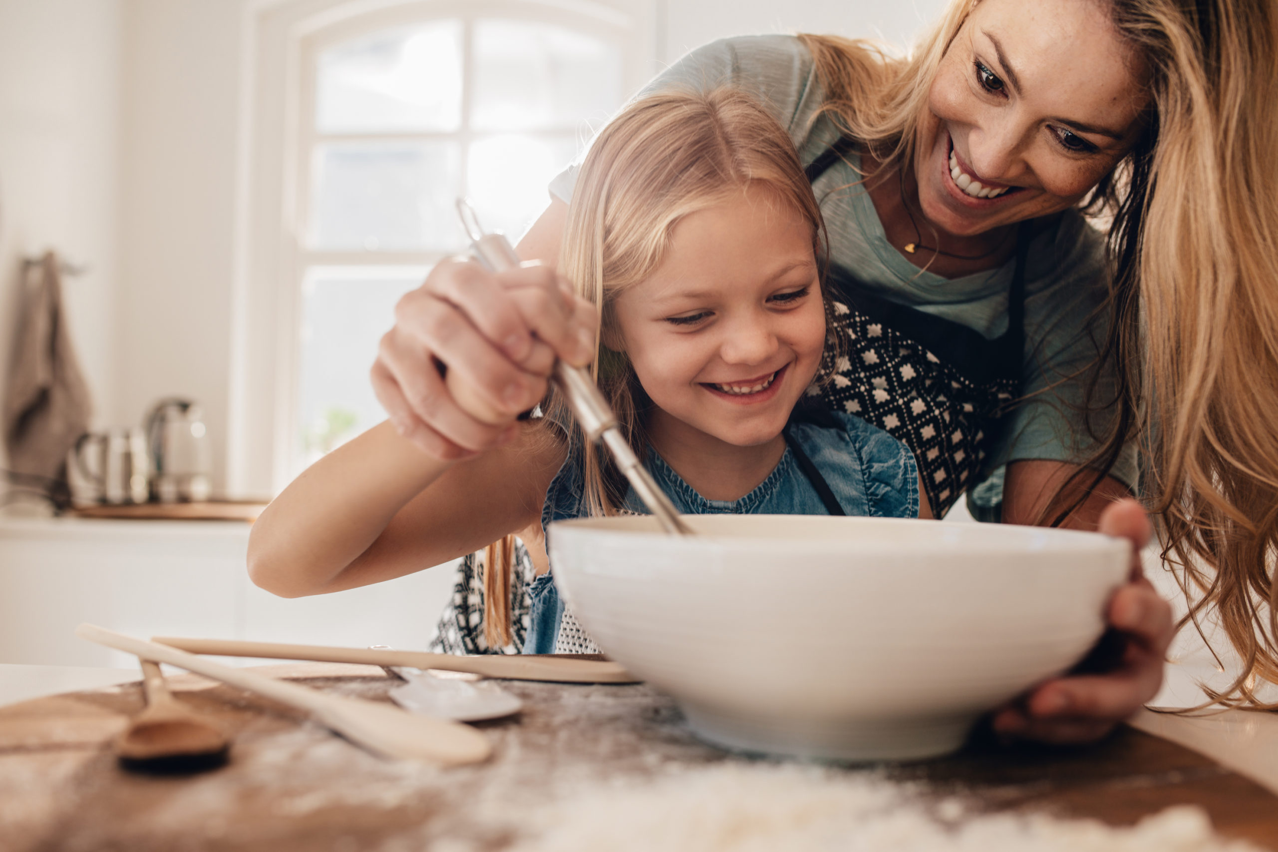Woman and child smiling while mixing batter in a bowl