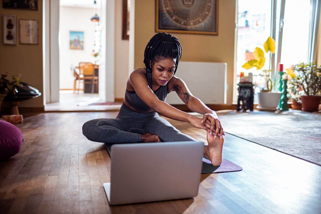 Woman Stretching on Floor in front of Laptop