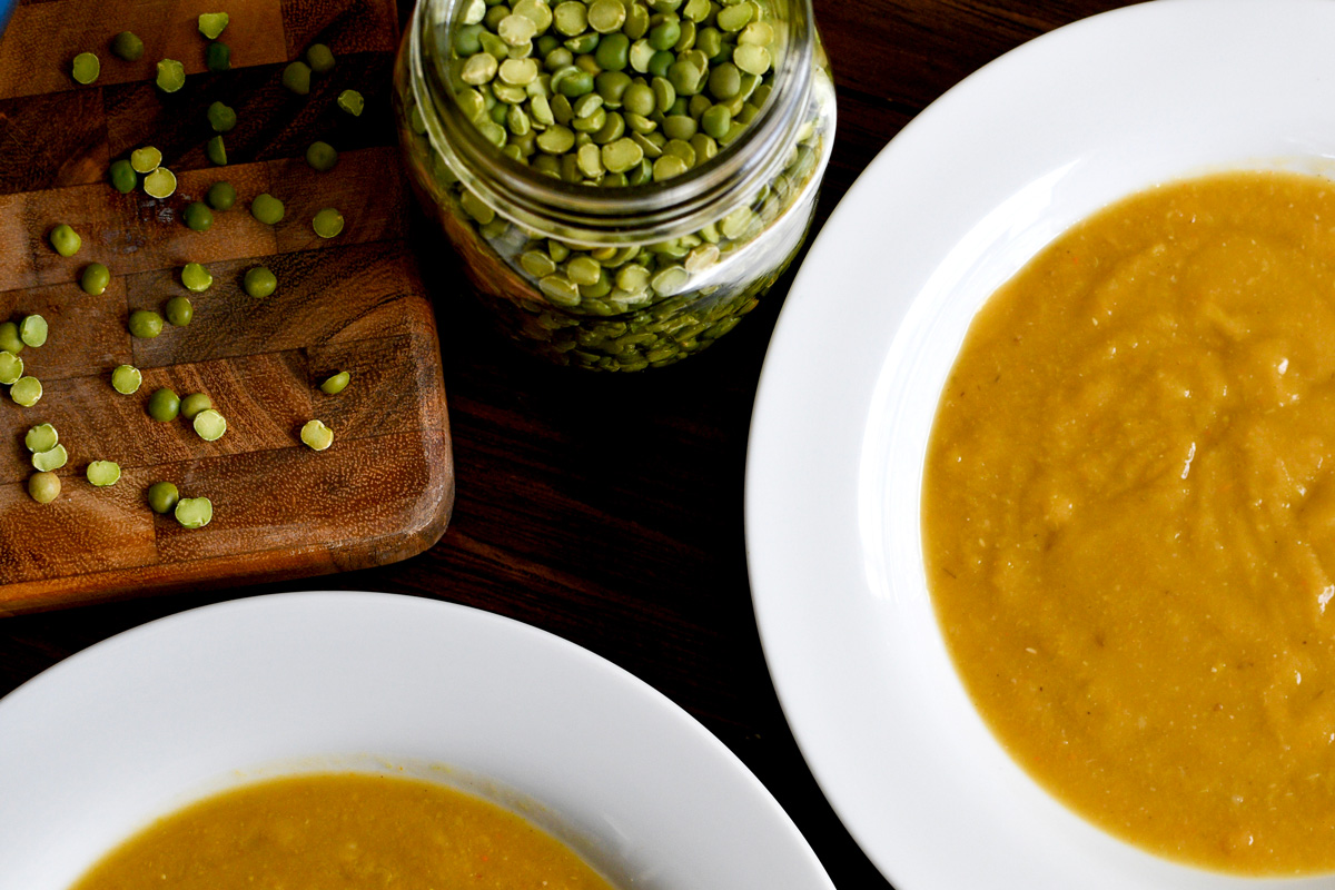 Two bowls of split pea soup with a jar of green split peas beside them