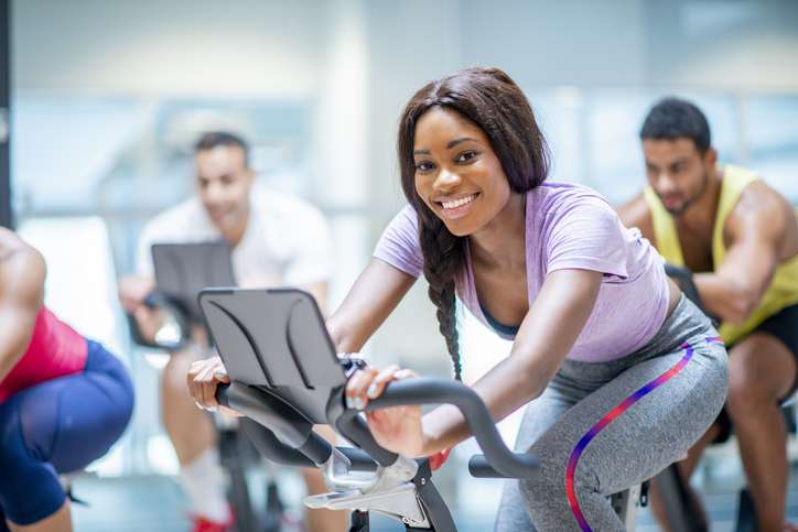 Woman smiling while riding a bike in a group exercise class