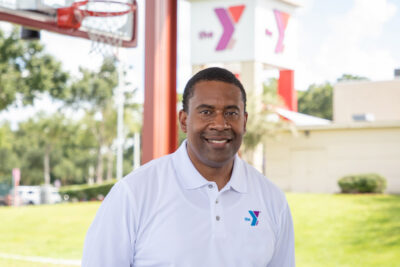 Photo of Kevin Bolding wearing white YMCA golf shit outside art the Frank DeLuca Sportsplex