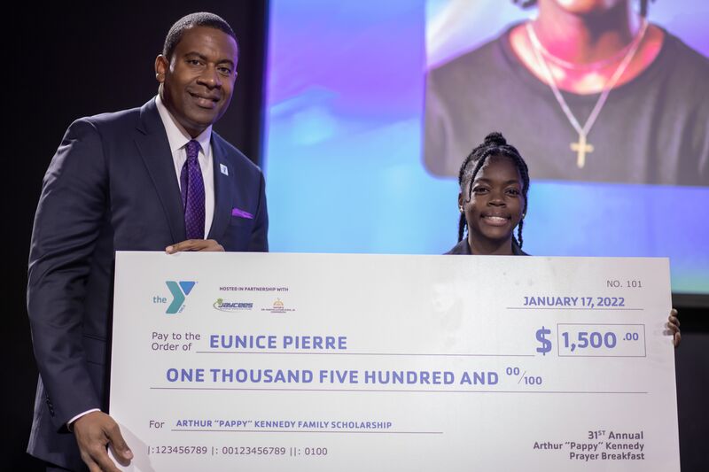 Teenager holding large scholarship check from the Arthur Pappy Kennedy family