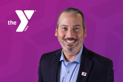Headshot of Dan Saginario with a purple chevron background and the white Y logo