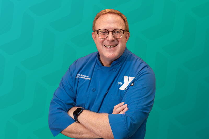 Headshot of Chef Gary Appelsies wearing a blue chefs coat with the YMCA logo on it