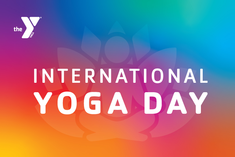 Rainbow background with white YMCA logo that says International Yoga Day with a lotus flower and person in cross legged meditative pose behind the text