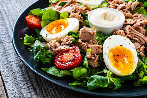 Tuna, boiled egg and vegetable salad on wooden background