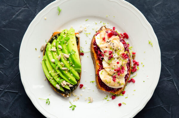 Healthy sandwich on sweet potato for breakfast or snack. One toasts with avocado and other with raspberry chia jam, peanut butter and banana with superfoods. Vegetarian food. Clean eating. Top view.