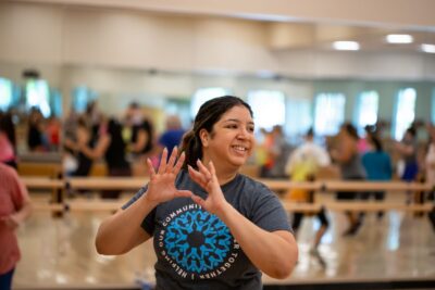 Woman dancing with hands up in a Zumba group exercise class