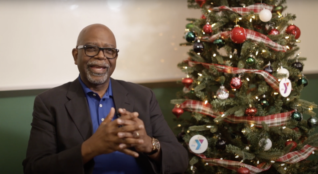 Screenshot of Reverend Archie Adam sitting next to Christmas Tree with YMCA logo ornaments