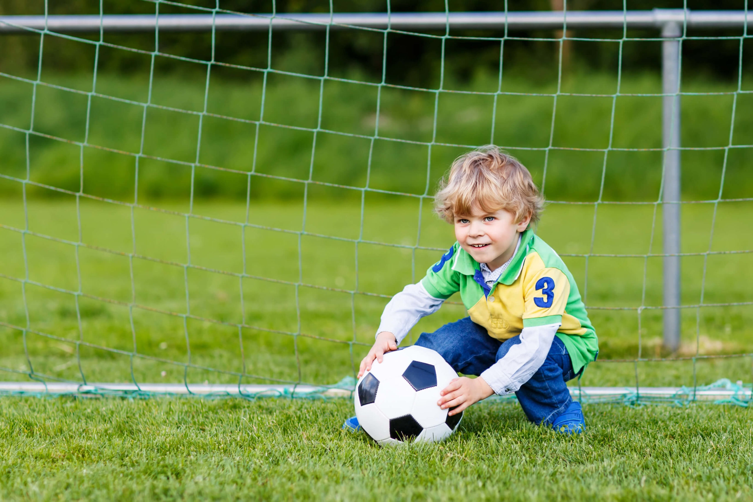 Young toddler on soccer field with soccer ball