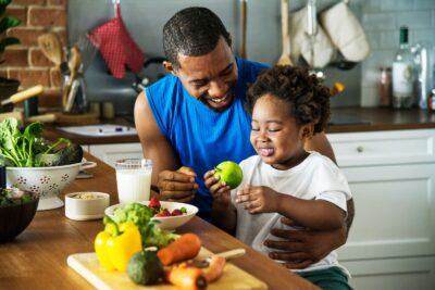 A father and child preparing food in the kitchen.