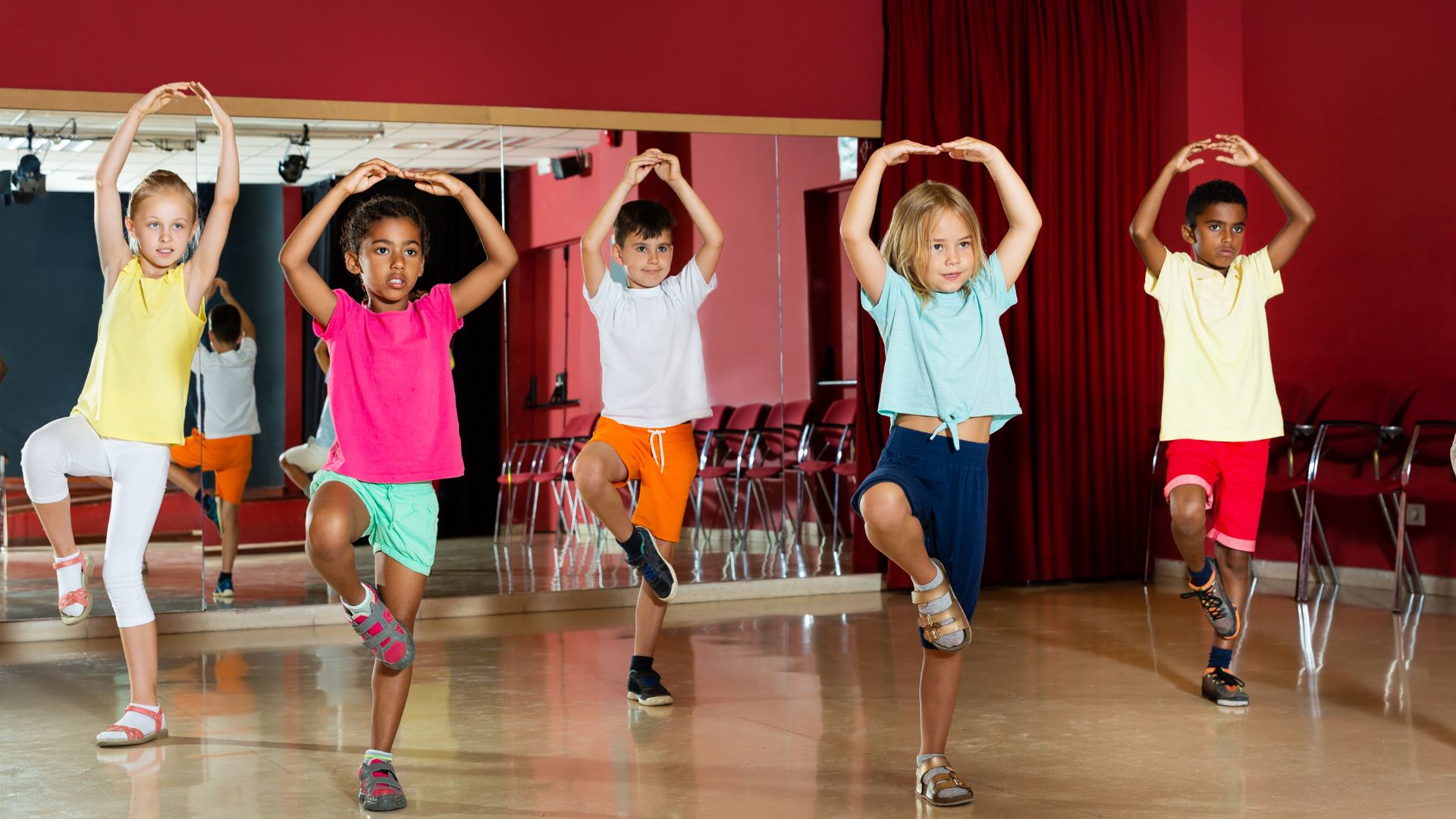 Group of young multicultural kids doing ballet in a studio room