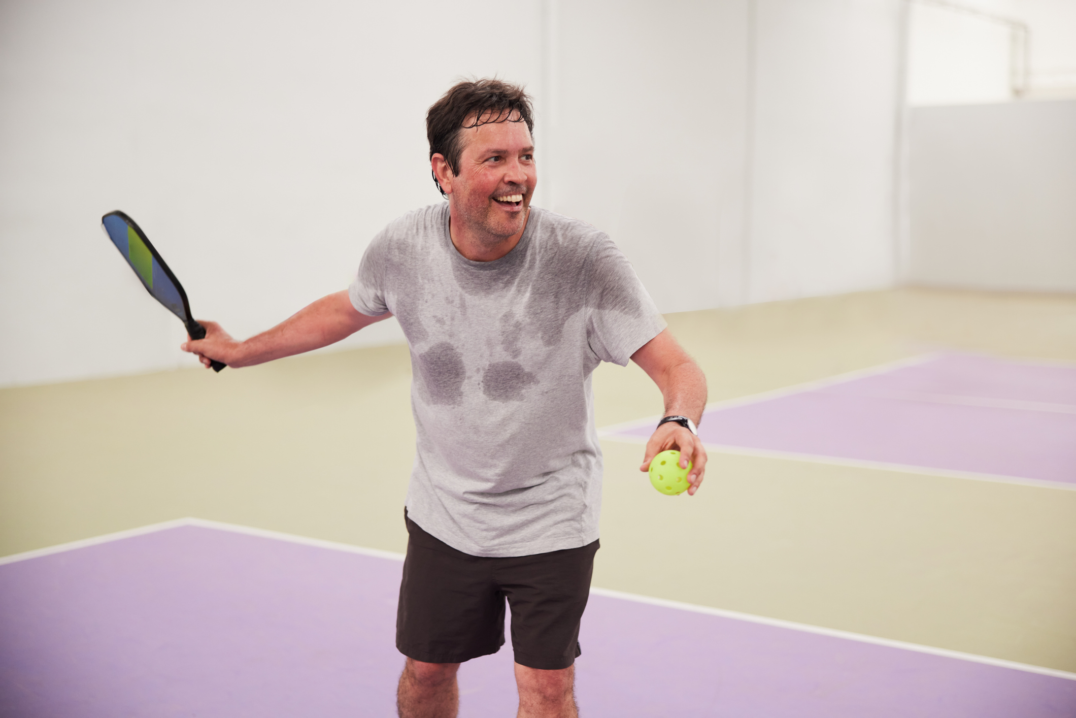 A middle-aged man plays pickleball.