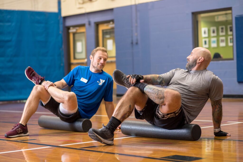 Image of personal trainer with his client stretching in a gym at the YMCA