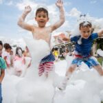 Two boys at YMCA camp outdoors jumping with bubbles all over them