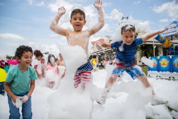 Two boys at YMCA camp outdoors jumping with bubbles all over them