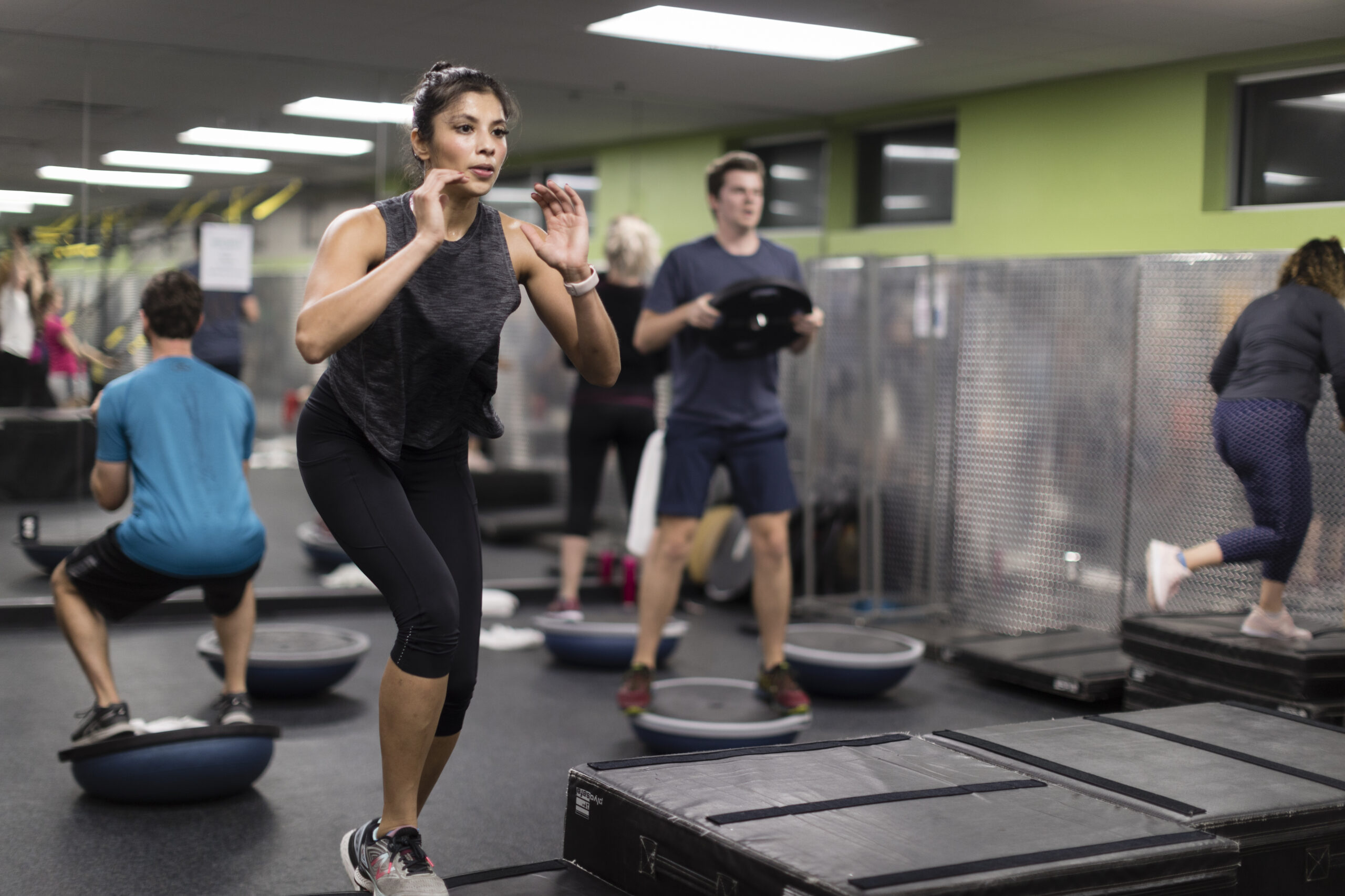 Woman working out in an indoor group exercise class at the YMCA with other participants in the background.