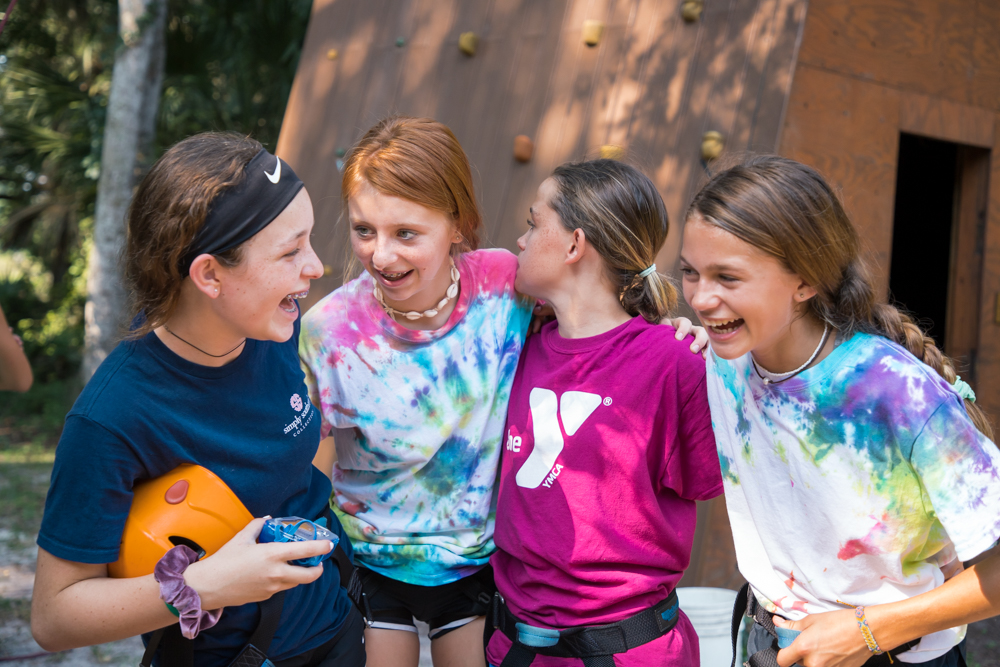 Four teen girls smiling and enjoying YMCA summer camp activities.
