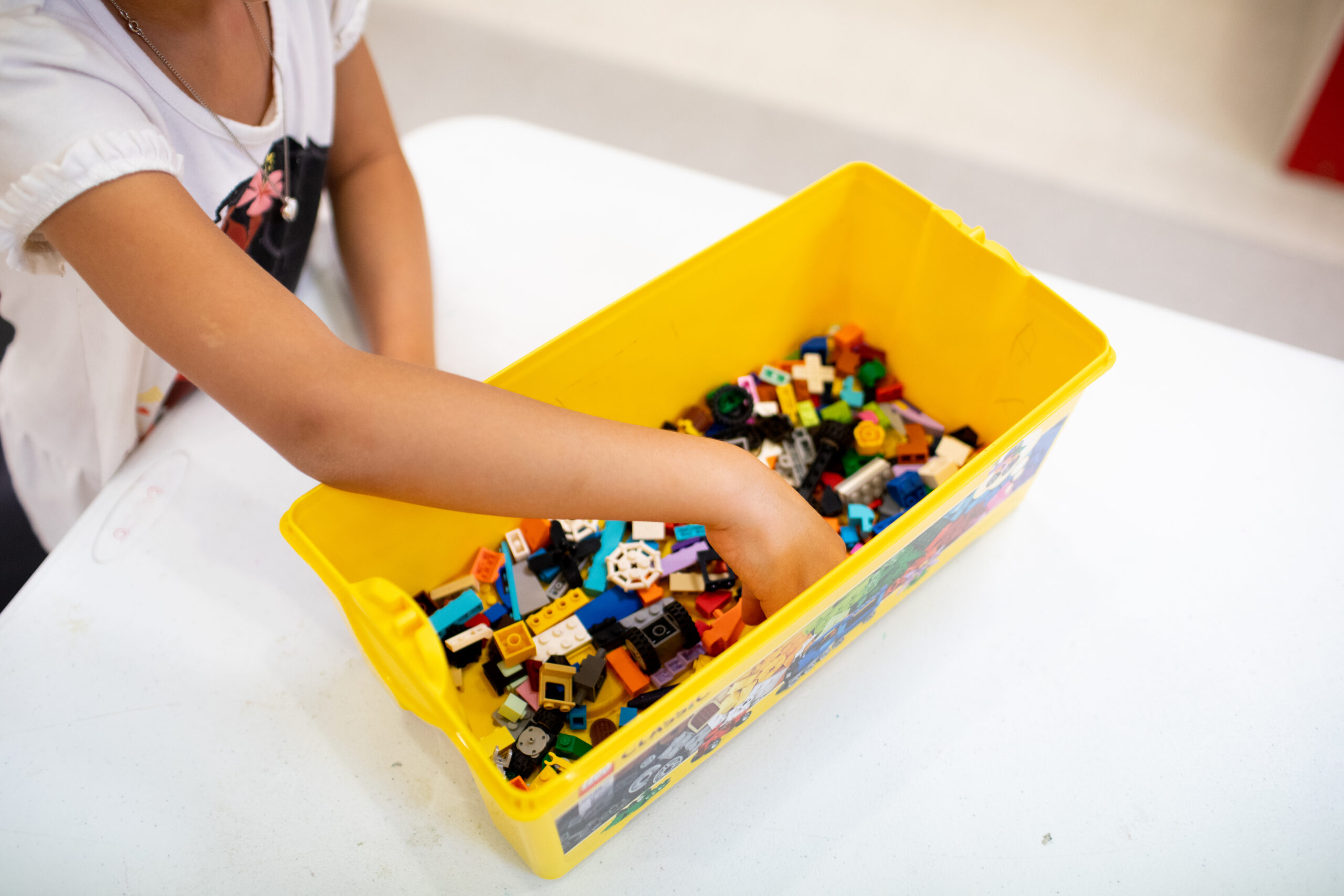 Child’s hand building with LEGO bricks at The PLAY Center childcare area at the YMCA.