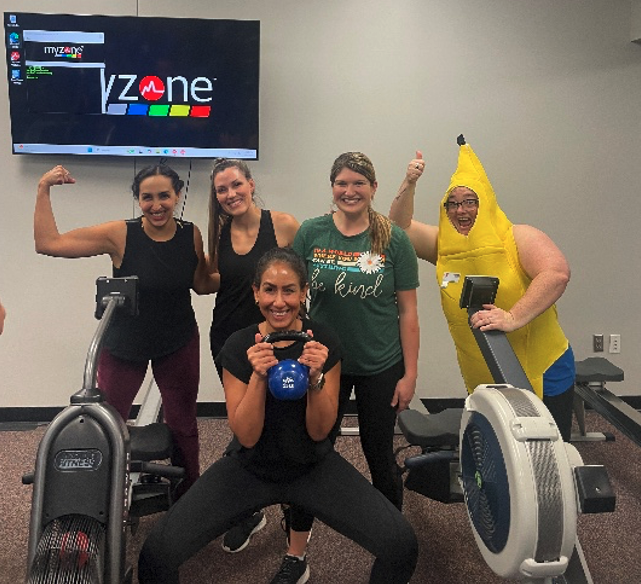 Five people using MyZone fitness equipment at the YMCA, tracking their workouts together.