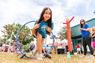 Girl running through a hula hoop that was set up for a child's obstacle course during Healthy Kids Day at Roper YMCA