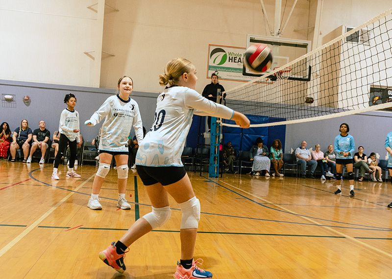 Girl about to hit a volleyball inside a gymnasium at the YMCA
