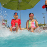A boy and girl splashing their feet at the edge of the pool at the YMCA