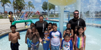Kids and swim instructors standing under a mushroom waterfall at the Osceola County YMCA