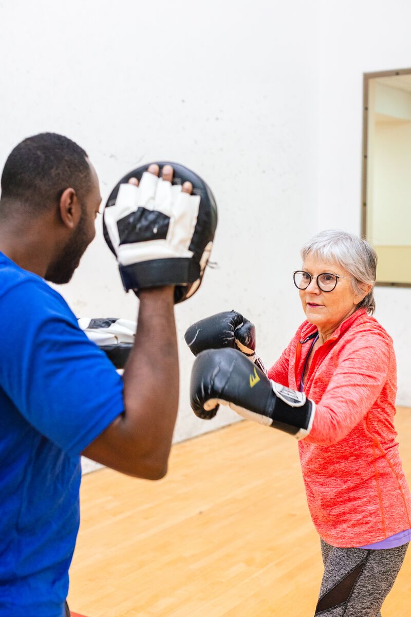 A woman boxing a man during her personal training session at the Downtown Orlando YMCA