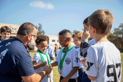 Child receiving a youth sports award from his coach at the YMCA