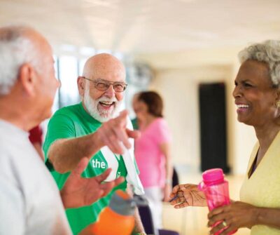 Seniors at the YMCA laughing together in a group exercise class