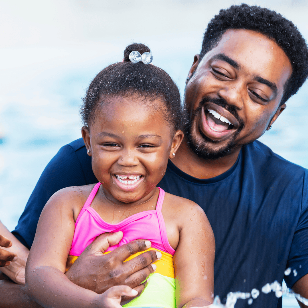 Father and daughter having fun splashing in a YMCA pool, enjoying summer activities together