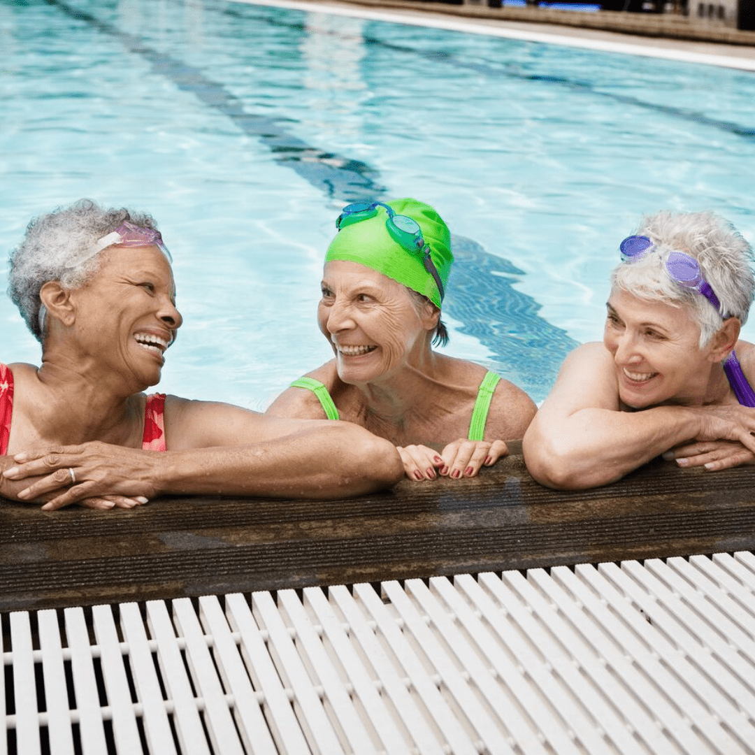 Three women smiling and relaxing poolside at a YMCA pool in Central Florida.”