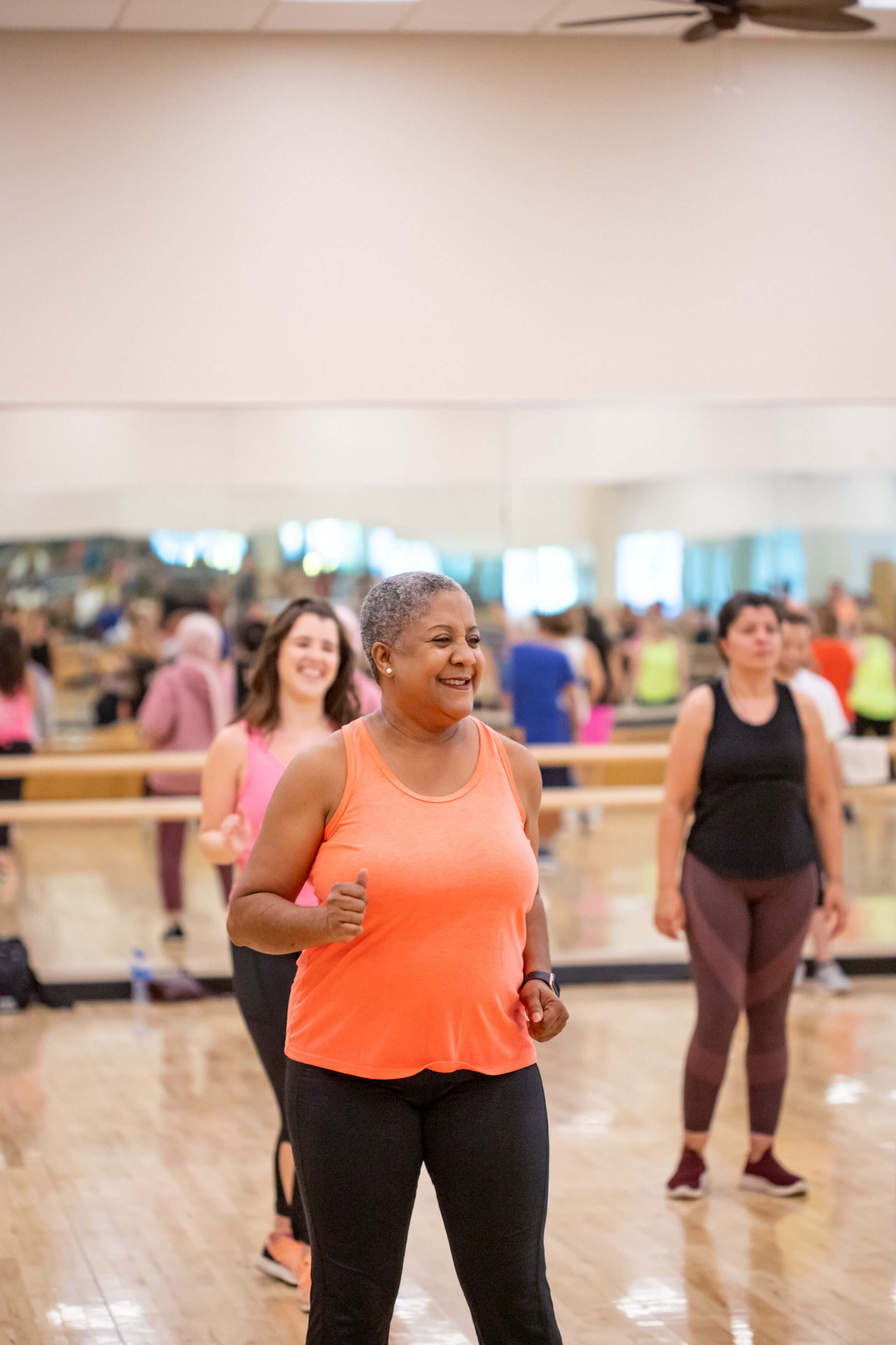 Two people participating in a group exercise class at the YMCA, smiling and moving together.