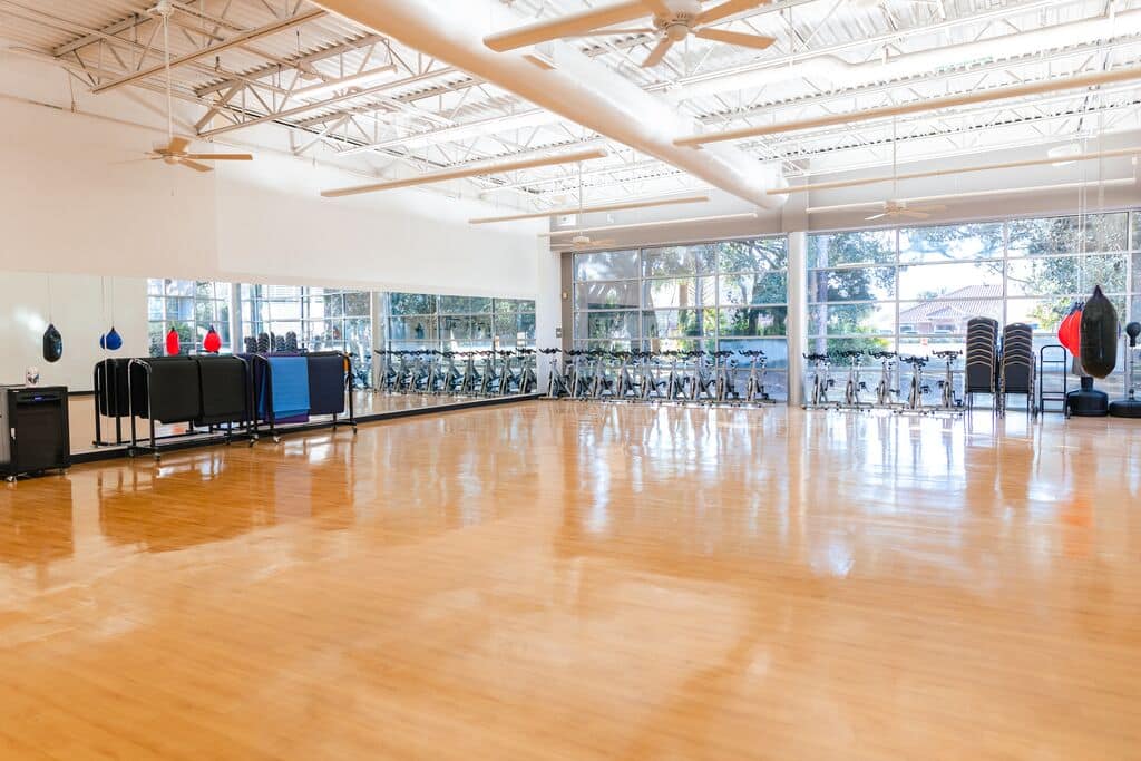 Group exercise studio at Parrish Health & Fitness Center, operated by the YMCA of Central Florida, set up for classes with mats and equipment.