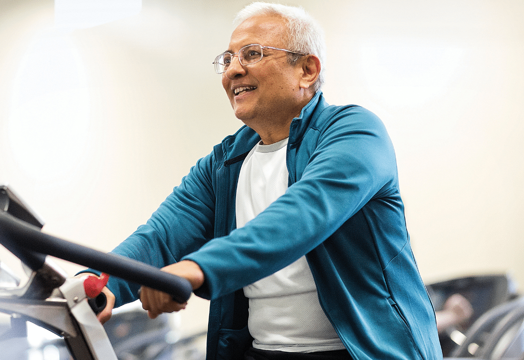 Senior man smiling while exercising on a stationary bike at the Parrish Health & Fitness Center.
