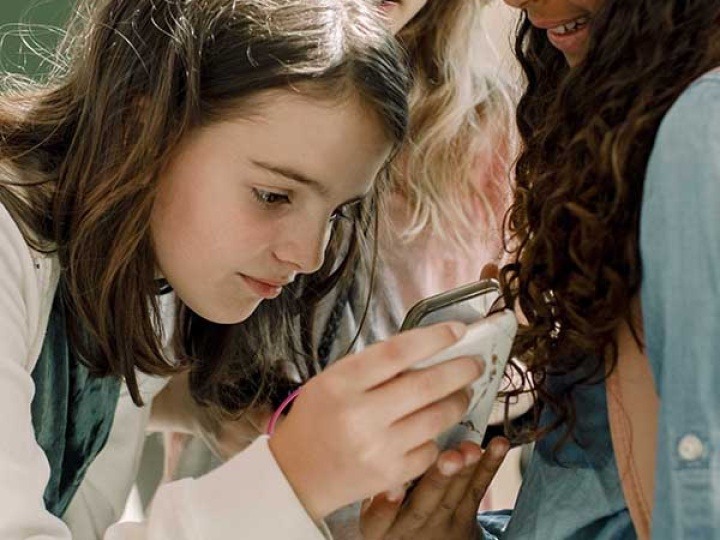 Young girl looking at a smartphone, highlighting the importance of digital safety for kids
