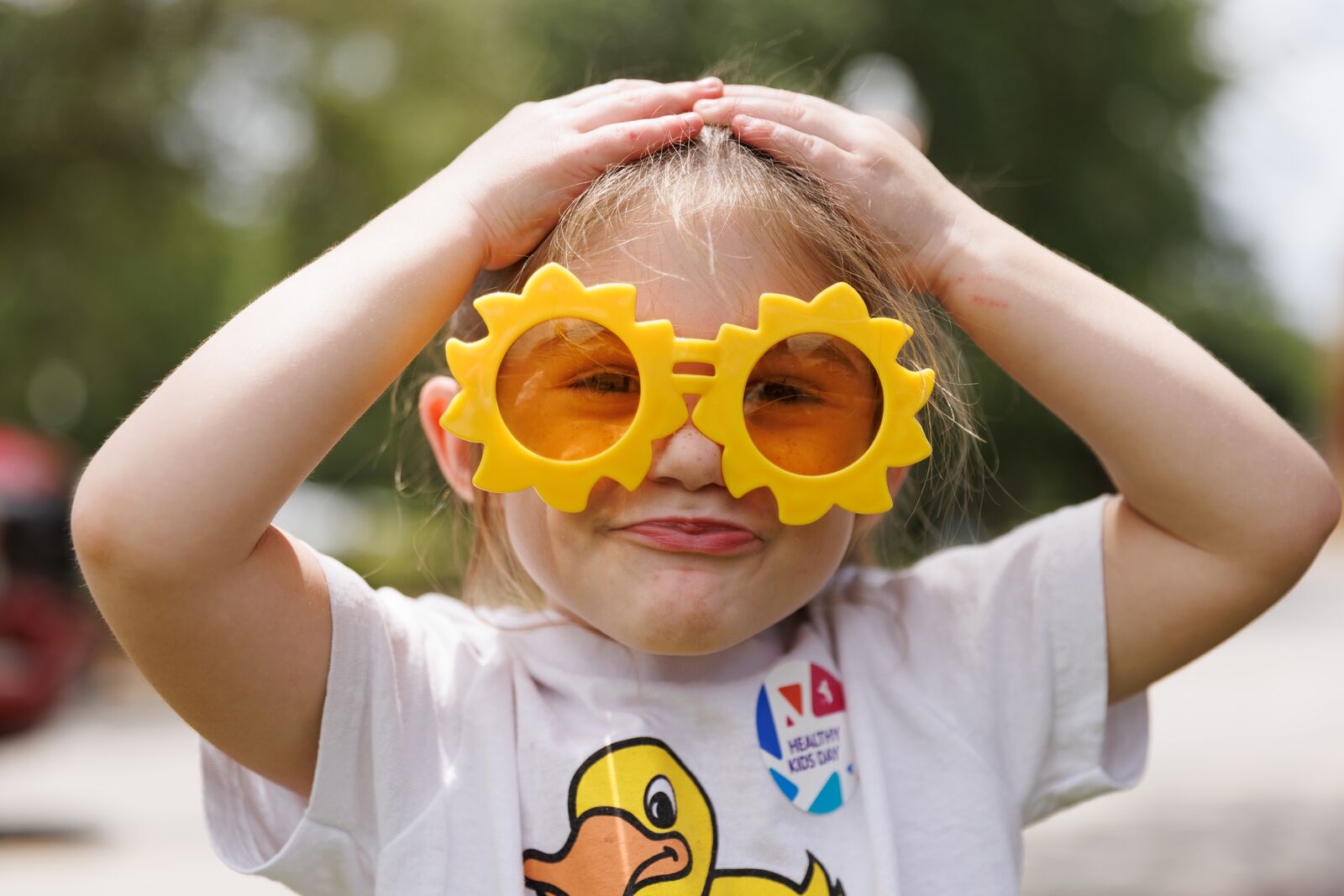 Child wearing sunglasses being playful at the YMCA, highlighting fun youth programs and member discounts.