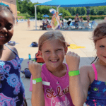Three swimmers showing their green band they earned after a free swim test at the YMCA