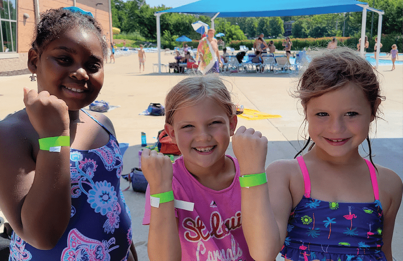 Three swimmers showing their green band they earned after a free swim test at the YMCA
