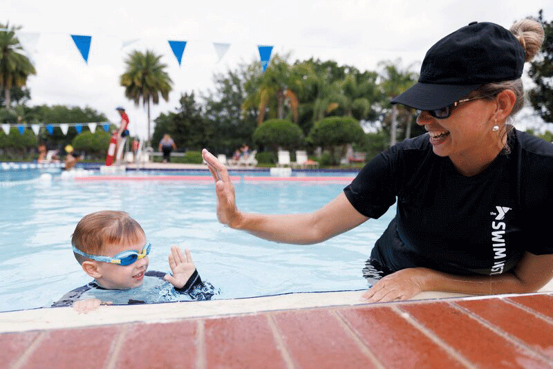 YMCA Swim Instructor high-fiving a swimmer during a swim lessons
