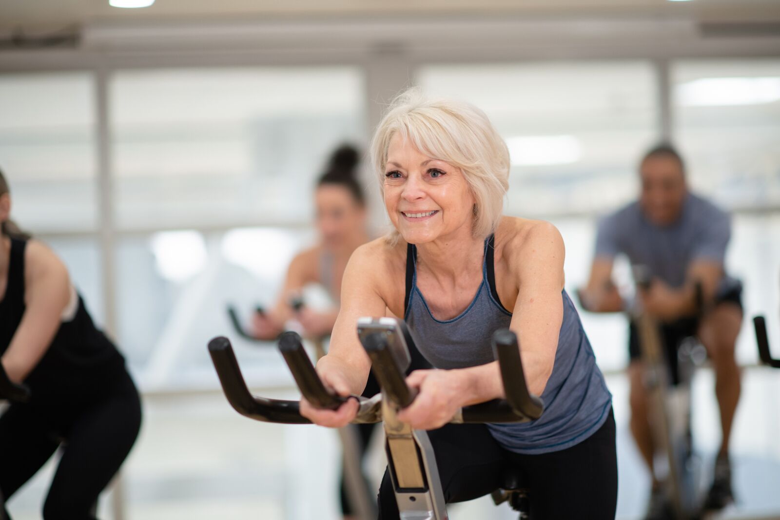 An older woman participates in a cycling workout at the YMCA, representing the Y’s commitment to helping older adults stay active, build strength, support their well-being, and enjoy meaningful connections through healthy movement.