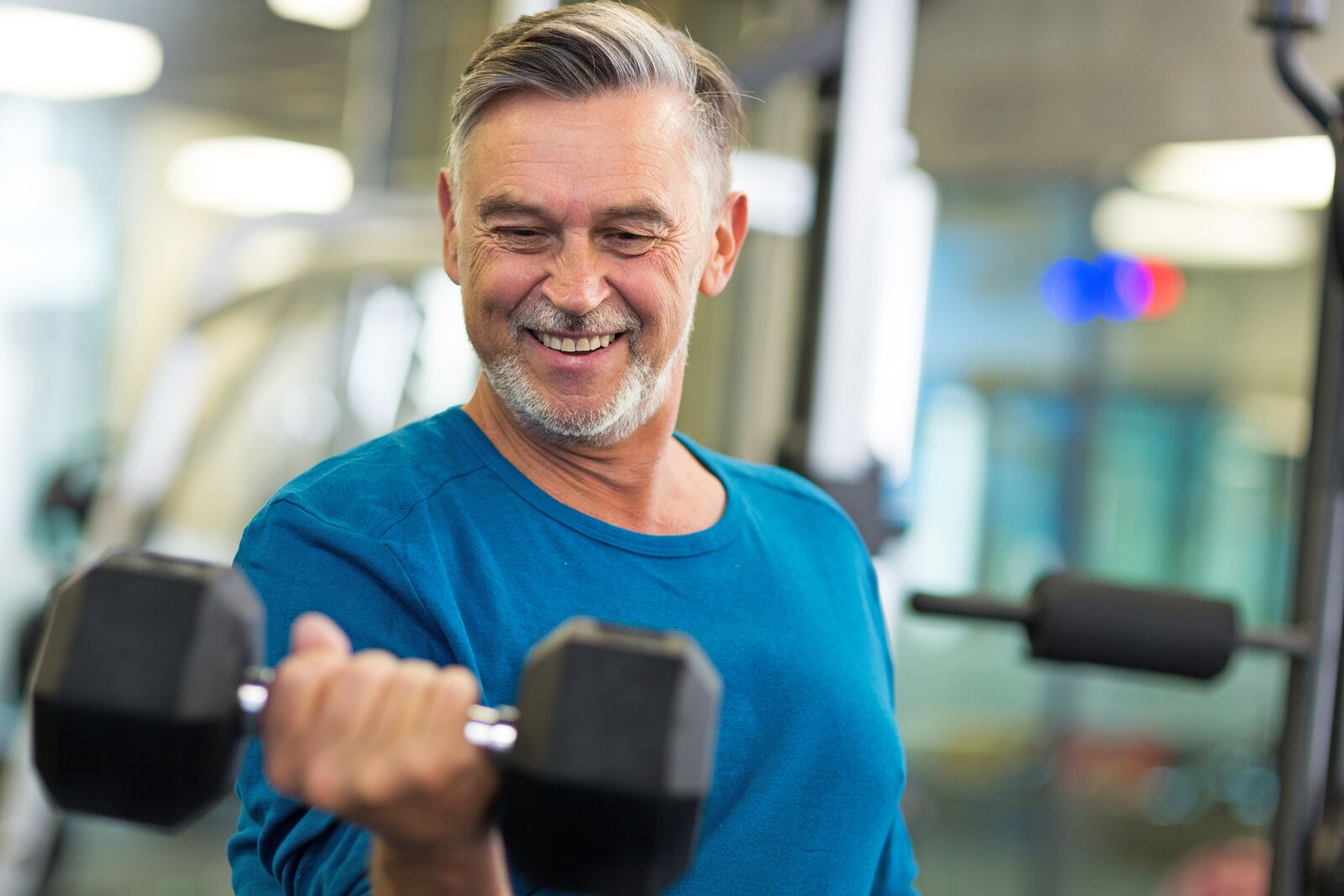 Older man exercising on strength equipment at the YMCA during a workout.
